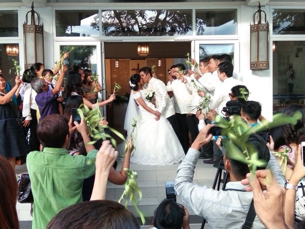 Newlyweds kissing at the church entrance while wedding guests cheer and take photos